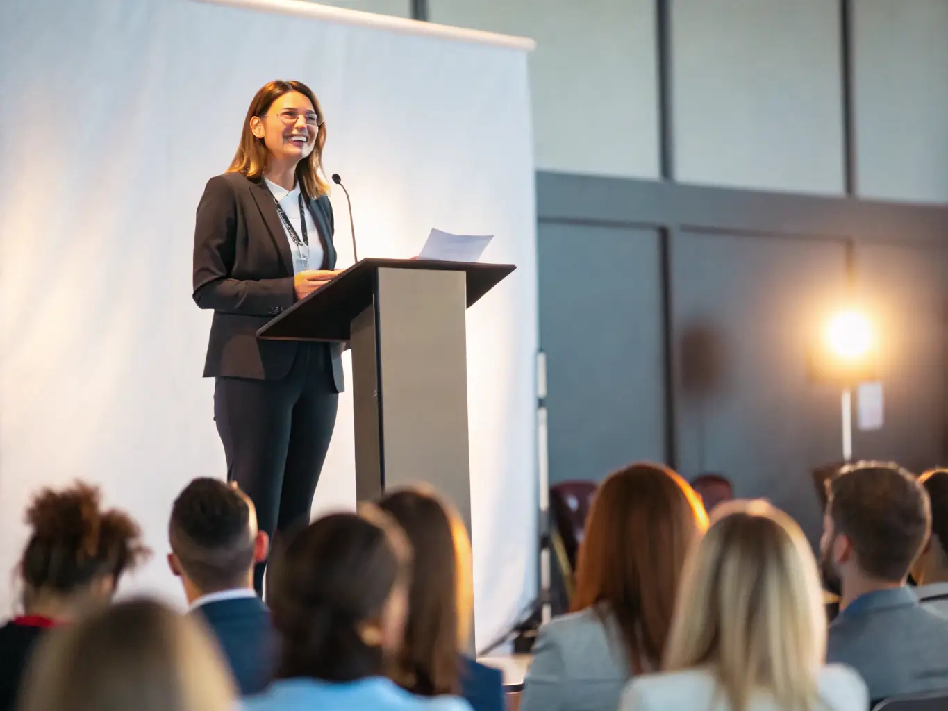 A photograph of a keynote speaker addressing a large audience at a past Startup Summit conference in India, with the speaker passionately gesturing and the audience attentively listening.